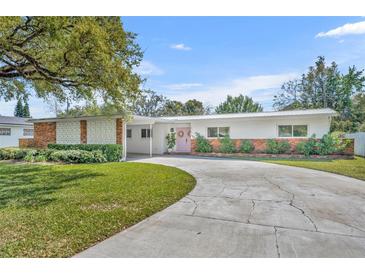 Charming single-story home with a spacious driveway, green lawn, and a lovely pink front door at 2732 Lion Heart Rd, Winter Park, FL 32792