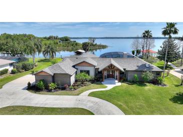 Stunning lakefront home with lush landscaping, circular driveway, and beautiful waterfront views at 29150 Beauclaire Dr, Tavares, FL 32778