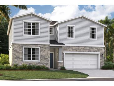Charming two-story home featuring stone accents, gray siding, attached two-car garage, and well-manicured landscaping at 33448 Seattle Slew Dr, Sorrento, FL 32776