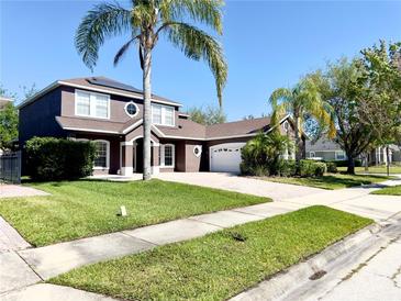 Charming two-story brown home featuring a well-manicured lawn, brick driveway, and a decorative round window at 7299 Vista Park Blvd, Orlando, FL 32829