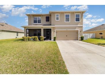 Two-story home featuring a two-car garage, well-maintained lawn, and inviting screened-in porch, enhancing its curb appeal at 9731 Pepper Tree Trl, Wildwood, FL 34785