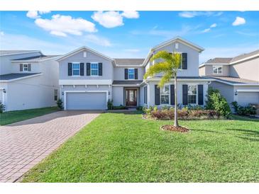 Charming two-story home with a well-manicured lawn, brick driveway, and lovely palm tree at 14315 Crestavista Ave, Clermont, FL 34714