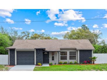 Charming home with a well-manicured lawn, gray color scheme, and a paved driveway leading to an attached garage at 1811 Oakgrove Ave, Deltona, FL 32725