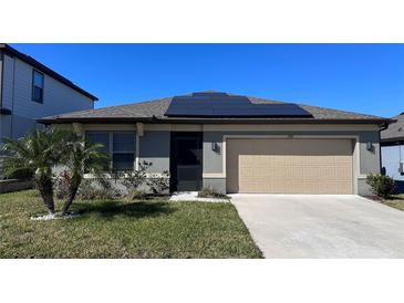 Charming single-story home featuring a well-manicured lawn, desert landscaping, solar panels and an attached garage at 398 Citrus Isle Loop, Davenport, FL 33837