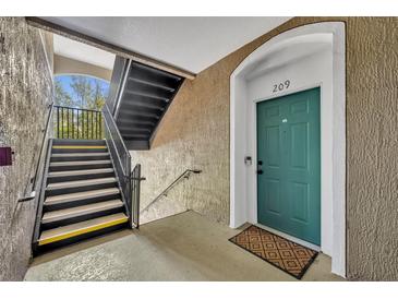 Welcoming entrance featuring a turquoise door and stairs with black railing, leading to a cozy condo unit at 581 Brantley Terrace Way # 209, Altamonte Springs, FL 32714