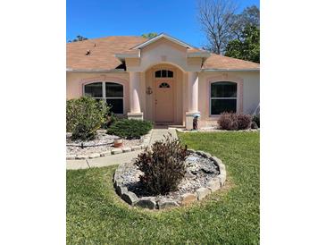 Charming home featuring a manicured front yard and inviting entryway with decorative columns at 6037 Hickory Grove Ln, Port Orange, FL 32128
