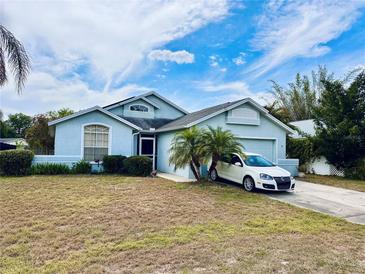 Attractive home with a blue exterior, mature palm trees, and a well-maintained front yard at 72 Saint Kitts Cir, Winter Haven, FL 33884