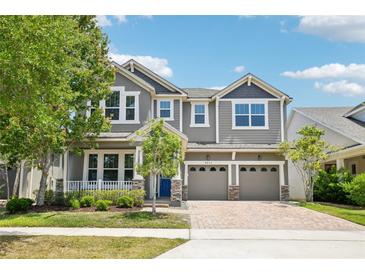 Charming two-story home featuring a brick driveway, two-car garage, and beautifully landscaped front yard at 8433 Corkfield Ave, Orlando, FL 32832