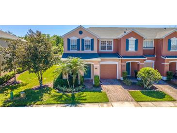 Charming two-story townhome with colorful facade, lush landscaping, and brick paved driveway at 16241 Old Ash Loop, Orlando, FL 32828