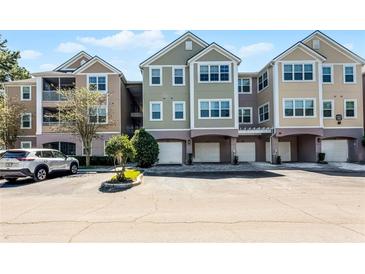 Three-story condominium building with individual garages and well-maintained landscaping at 3384 Corona Village Way # 202, Orlando, FL 32835