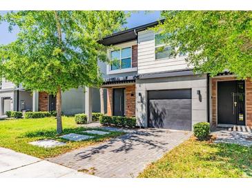 Charming two-story home with a brick driveway and one-car garage, surrounded by lush green landscaping at 4445 Le Reve Ct, Kissimmee, FL 34746