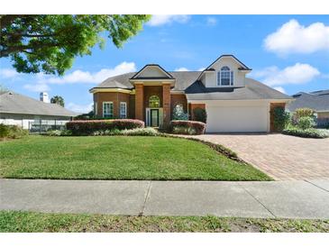 Charming two-story brick home with a manicured lawn and beautiful landscaping creating a welcoming curb appeal at 437 Wilmington Cir, Oviedo, FL 32765