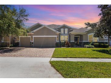 Beautiful home featuring a three-car garage, manicured lawn, brick driveway, and stunning curb appeal at 2731 Cypress Tree Trl, St Cloud, FL 34772