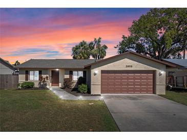 Charming single-story home with a well-manicured lawn, two-car garage, and a brick facade against a sunset sky at 2955 Foxcroft Ln, South Daytona, FL 32119