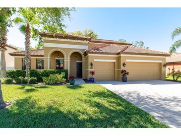 Charming home with a terracotta roof, arched entry, manicured lawn and a two-car garage on a sunny day at 2956 Falconhill Dr, Apopka, FL 32712