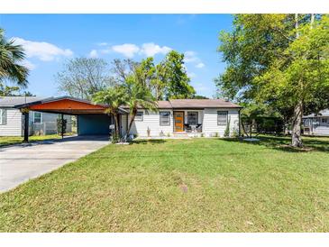 Charming single-story home featuring a well-manicured lawn and a covered carport, perfect for easy parking at 407 E Jersey St, Orlando, FL 32806