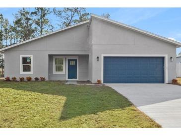 Charming single-story home with a blue door and a well-manicured front yard at 4774 Sw 142Nd Place Rd, Ocala, FL 34473