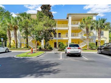 Charming yellow condominium complex with white railings, surrounded by lush landscaping and convenient parking at 806 Lucaya Loop, Davenport, FL 33897