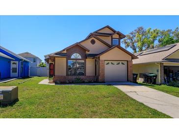 Charming tan two-story home with a well-manicured lawn and attached one car garage on a sunny day at 10020 Creekwater Blvd, Orlando, FL 32825