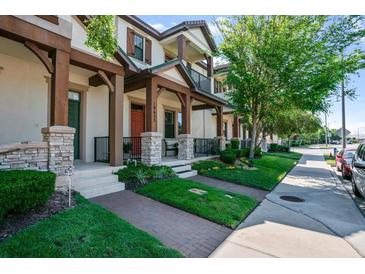 Charming townhouse with stone accents, well-manicured lawn, and inviting covered entryway at 10655 Village Lake Rd, Windermere, FL 34786