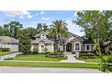 Charming home featuring stone accents, a well-manicured lawn, and lush landscaping at 116 Cherry Creek Cir, Winter Springs, FL 32708