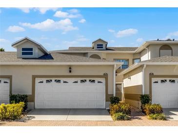 Attractive townhouse featuring a two-car garage, manicured landscaping, and a secure gated entrance at 13326 Fountainbleau Dr, Clermont, FL 34711