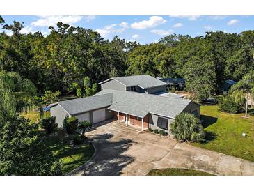An aerial view of a single-Gathering home with a gray roof, well-manicured lawn, and mature trees at 1661 Votaw Rd, Apopka, FL 32703