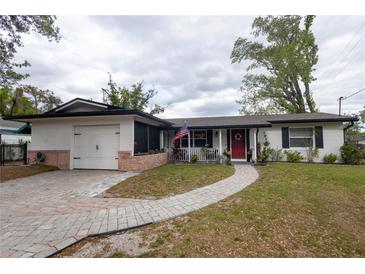 Charming single-story home featuring a welcoming front porch, red door, and brick-lined pathway and garage at 1938 Eastbrook Blvd, Winter Park, FL 32792