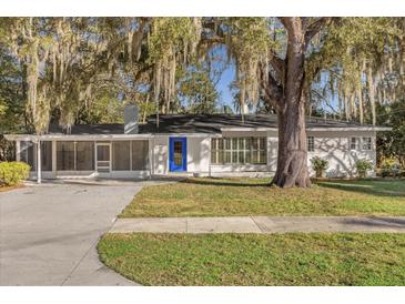 Charming single-story home featuring a blue front door, lush landscaping, and beautiful trees draped in Spanish moss at 719 Se 24Th St, Ocala, FL 34471