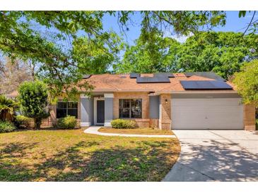 Charming brick home with well-manicured lawn, solar panels, and inviting walkway at 10400 Hunters Trail Ct, Orlando, FL 32817