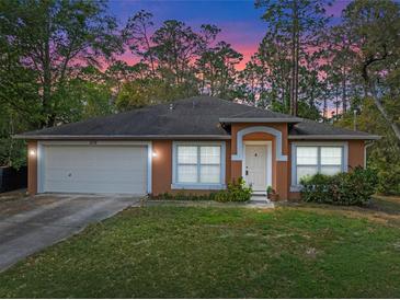 Charming single-story home featuring a two-car garage, warm stucco exterior, and well-manicured front lawn at 1234 1St Ave, Deland, FL 32724