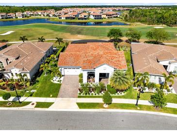 Beautiful aerial view of a house with a red tile roof overlooking a golf course and a lake in a planned community at 13349 Alderley Dr, Orlando, FL 32832