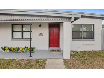 Home's front entrance features a red door, welcoming mat, and freshly planted flowers at 1633 Colton, Orlando, FL 32822