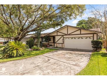 Charming home exterior featuring a well-manicured lawn, mature trees, and a two-car garage at 2508 Osage Trl, Fern Park, FL 32730