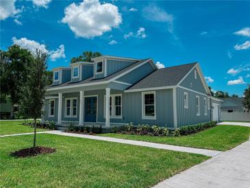 Charming two-story home features dormer windows, blue siding, a well-manicured lawn, and a welcoming front porch at 311 W Delaware Ave, Lake Helen, FL 32744