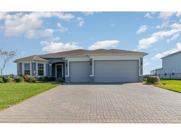 Charming single-story home featuring a brick driveway, neutral paint, manicured lawn, and two-car garage at 4672 Marina Row Dr, Orlando, FL 32820