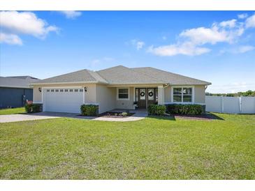 Charming single-story home boasts a lush green lawn, well-manicured landscaping, and an attached two-car garage at 130 Islabella Way, Groveland, FL 34736
