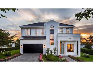 Stunning two-story home featuring lush landscaping, black trim windows, and a modern garage door at 1803 Florinda Dr, Orlando, FL 32804