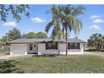 Charming single-story home featuring a manicured lawn, freshly painted white exterior, and beautiful palm trees at 211 Agua Vista St, Debary, FL 32713