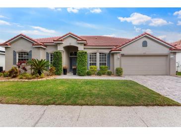 Well-maintained single-story home with a red tile roof, manicured landscaping, and a brick driveway at 2359 Baronsmede Ct, Winter Garden, FL 34787