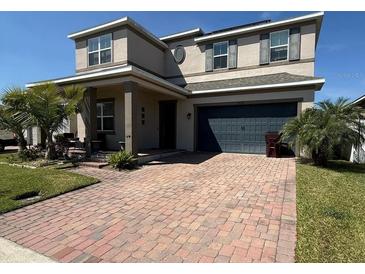 Charming two-story home featuring a brick driveway and a well-maintained lawn with verdant palm trees at 4783 Riverwalk Dr, St Cloud, FL 34771