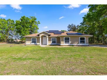 Charming single-story home with lush lawn, solar panels, and well-manicured landscaping at 8499 Se 155Th, Summerfield, FL 34491