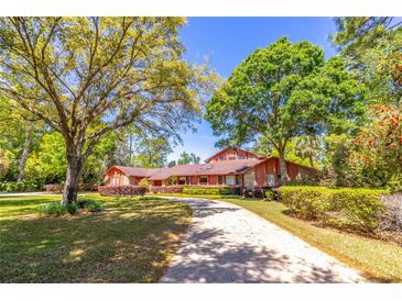 Charming home featuring a long driveway, mature trees, and well-maintained landscaping at 160 Archers Pt., Longwood, FL 32779