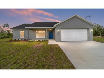 Charming single-story home featuring a blue front door and a two-car garage at 23810 Sw Indian Hill Dr, Dunnellon, FL 34431