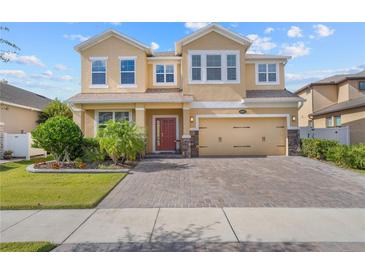 Inviting two-story home with a brick driveway and manicured landscaping under a blue sky at 3087 Somerset Park Dr, Orlando, FL 32824