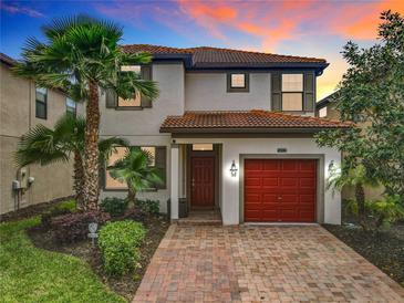 Charming two-story home boasts a red-tiled roof, red garage door and lush landscaping, creating inviting curb appeal at 5412 Solterra Cir, Davenport, FL 33837