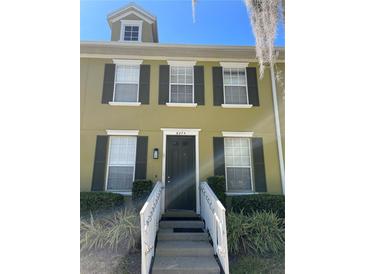 Townhouse exterior features a private entrance with black door, white rails, three windows, and black shutters at 6274 Bristol Channel Way, Orlando, FL 32829