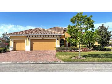 Charming single-Gathering home featuring a well-manicured lawn, red brick driveway, and a spacious three-car garage at 801 San Raphael St, Poinciana, FL 34759