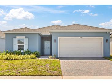 Charming single-story home featuring a two-car garage, well-kept lawn, and a welcoming front entrance at 1174 Tupelo Trl, Haines City, FL 33844