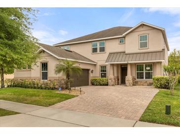 Charming two-story home featuring a brick driveway, stone accents and meticulously landscaped front yard at 12002 Angle Pond Ave, Windermere, FL 34786